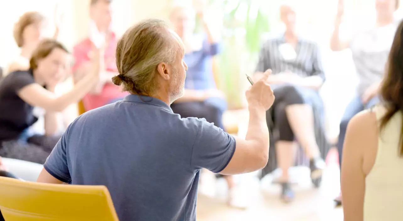 Trainer sitzt vor Gruppe und hält das Seminar Gruppendynamik